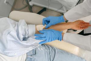 Close-up of doctor putting an IV drip to patient intravenously in hospital ward photo