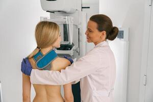 Smiling doctor prepairing woman before doing mammogram x-ray to check for breast cancer at hospital photo