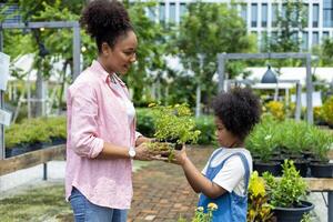 African mother and daughter is choosing ornamental plant and blooming flower pot from the local garden center nursery during summer for weekend gardening and outdoor photo