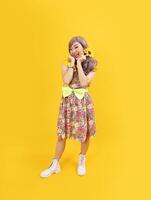 Asian hippie woman dress in 80s vintage fashion with colorful retro clothing while posing isolated on yellow background for fancy outfit party and pop culture concept photo