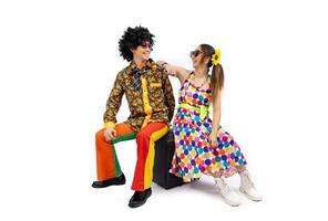 asiático hippie Pareja vestir en Años 80 Clásico vestir Moda con vistoso retro canguelo disco ropa mientras bailando aislado en blanco antecedentes para lujoso atuendo fiesta y popular cultura uso foto