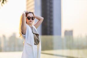 Luxury young Asian CEO woman entrepreneur standing on the rooftop looking to the sun with skyscraper and cityscape on the background photo