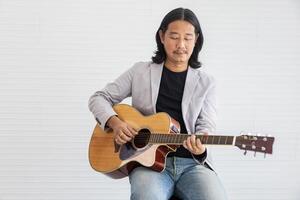 Asian artist singing song and playing acoustic guitar on white background for live acoustic concert and music related concept photo