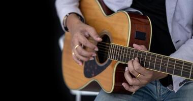 Close up shot of guitarist playing acoustic guitar on black background with copy space for folk music and unplugged performance concept photo