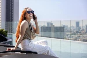 Luxury young Asian CEO woman entrepreneur using mobile phone with skyscraper and cityscape on the background for business communication and urban lifestyle usage photo