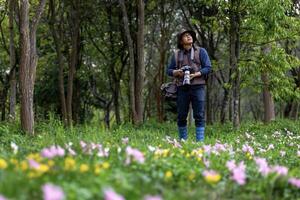 fotógrafo es tomando foto mientras explorador en el bosque bosque con salvaje flor prado para topografia y localizando raro biológico diversidad y ecologista en campo estudiar uso