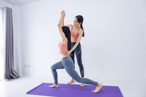 Asian women practicing sun salutation yoga indoor with her class trainer leg stretching position to control breathing in and out for good health photo