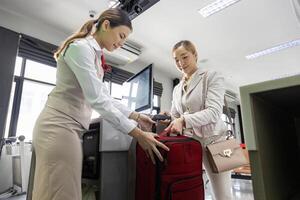 Asian passenger is checking in her big luggage bag to airline ground crew at departure gate into the airplane for measuring weight before boarding into plane photo