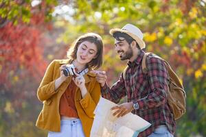 Happy caucasian couple are walking together in public park during autumn with maple and beech tree while looking at camera photo for fall color travel destination and family happiness