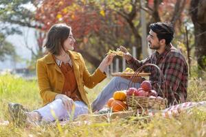 Happy caucasian farmer couple have picnic dating with food from organics homegrown produce harvest like apple, squash and pumpkin with fall color from maple tree during autumn season photo