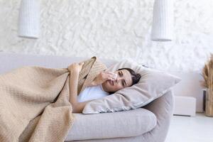 Close-up photo of a young beautiful woman alone at home in depression, crying, lying on the sofa, sad in the living room