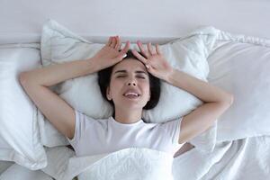 Top view, depressed woman lying in bed crying and screaming with sadness. photo