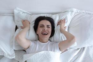Top view, depressed woman lying in bed crying and screaming with sadness. photo