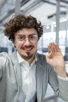 Vertical shot, a businessman in the office is talking to colleagues and friends using an application on a smartphone, a mature man in a business suit inside the office is smiling friendly. photo