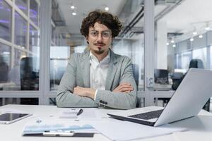 Portrait of successful businessman behind paper work, man in shirt smiling and looking at camera, financier boss inside office using laptop in work at workplace photo