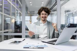 Portrait happy businessman financier, mature man with breed looking at camera and smiling, holding report with good achievement results and financial indicators celebrating victory, triumph gesture. photo