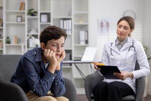 Admission of a young upset teenage boy to a pediatrician, a female doctor asks a young teenager about the disease, writes down information. photo