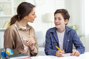 Home education, woman teaches boy at home sitting at table in living room, mother explains educational material to son doing homework together. photo