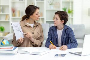 Home education, woman teaches boy at home sitting at table in living room, mother explains educational material to son doing homework together. photo