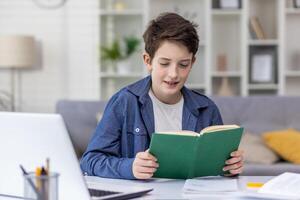 Concentrated teenage boy sitting in his room reading his favorite book, doing homework, concept of distance learning, tutoring. photo