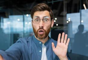 Serious man talking on a call with colleagues, the man uses an application on a smartphone and looks at the camera, pov, webcam view. photo