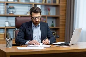 Serious thinking businessman behind paper work, senior experienced boss working concentratedly sitting inside office at table, financier investor signing contract. photo