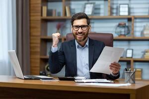 Portrait happy businessman financier, mature man with breed looking at camera and smiling, holding report with good achievement results and financial indicators, celebrating victory, triumph gesture. photo
