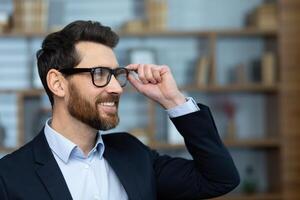 Close up portrait of mature successful businessman, man inside home office in business suit looking towards window, satisfied with achievement results boss with beard. photo