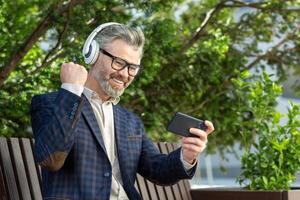 Mature executive man in a suit relaxes with music outside the office, showcasing work-life balance and leisure time. photo