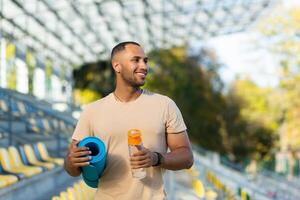 Portrait of sportsman with bottle of water, man resting walking stadium for training, young athlete yoga and fitness trainer. photo