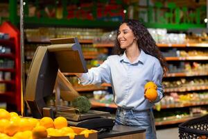 Young woman shopper in supermarket uses self-service scales, smiling Hispanic woman weighs fruits and vegetables in large store. photo