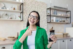 Young beautiful female nutritionist in glasses and green shirt advertises and recommends chocolate. He looks at the camera, points to the chocolate, poses, smiles. photo