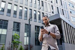 A man stands in front of a building, engrossed in his cell phone. Serious and thinking typing smartphone photo