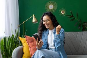 un joven mujer es en la foto adentro, demostración un Estallar de alegría y emoción como ella mira a su teléfono inteligente, posiblemente celebrando un pedazo de bueno Noticias o un personal logro.