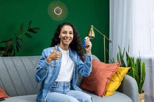 Satisfied woman recommending medicine for asthma and to ease breathing, Hispanic woman smiling and looking at camera holding inhaler. photo