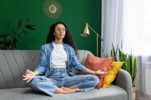 A woman finds peace as she meditates on a couch in her serene living room. photo