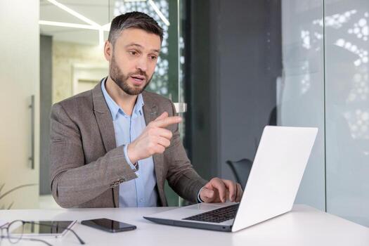 enfocado empresario en un inteligente casual atuendo teniendo un grave discusión durante un conferencia llamada en un moderno oficina. foto