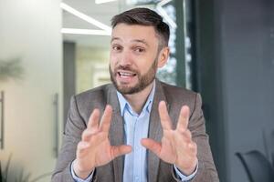 profesional masculino en un traje atractivo en un conferencia llamada mientras mirando a el cámara en un moderno oficina ajuste. foto