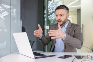 Focused businessman engaged in a serious conversation over a call in a modern office setting. photo