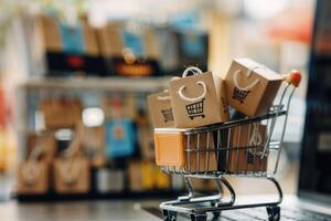 A shopping cart filled with boxes is in front of a laptop. photo