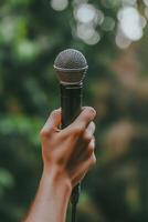 A hand holding up a microphone in a professional setting, symbolizing the power of speech and communication. photo