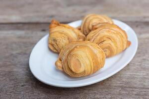 Curry puffs are a snack of central in Thailand. It is small pie that contains chicken and potatoes in a white plate on a wooden table. photo