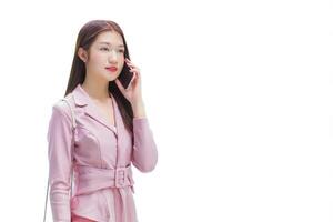 Young asian business professional woman in pink dress is calling phone seriously confident with someone at building while isolated white background. photo