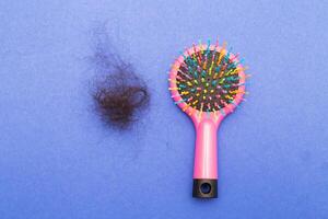 Hair loss a plastic multicolored comb on a paper blue background with copy space close up. photo