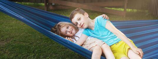 children brother and sister resting in the garden on a hammock photo