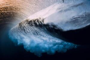 Barrel wave crashing in ocean with sunset or sunrise. Underwater view of surfing wave photo