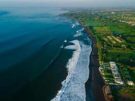 Aerial view of black sand beach with ocean waves in Keramas, Bali photo