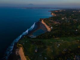 Drone view of coastline with beaches and ocean with waves at sunset in Bali. Balangan beach photo