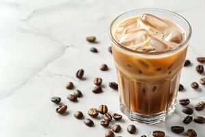 Chilled iced coffee with milk in a glass on a white marble table, surrounded by beans, with room for text photo