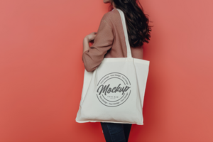 tote bag mockup with a background of a woman holding a white shopping bag psd